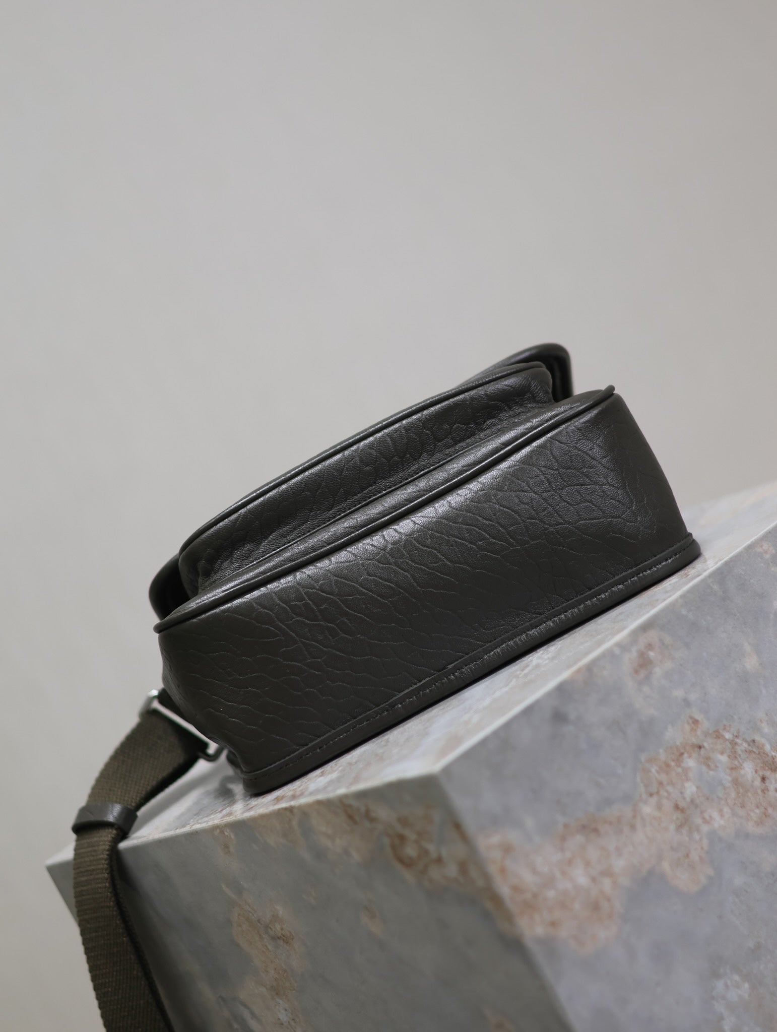 YSL crossbody bag rear view in black textured leather, strap across the back