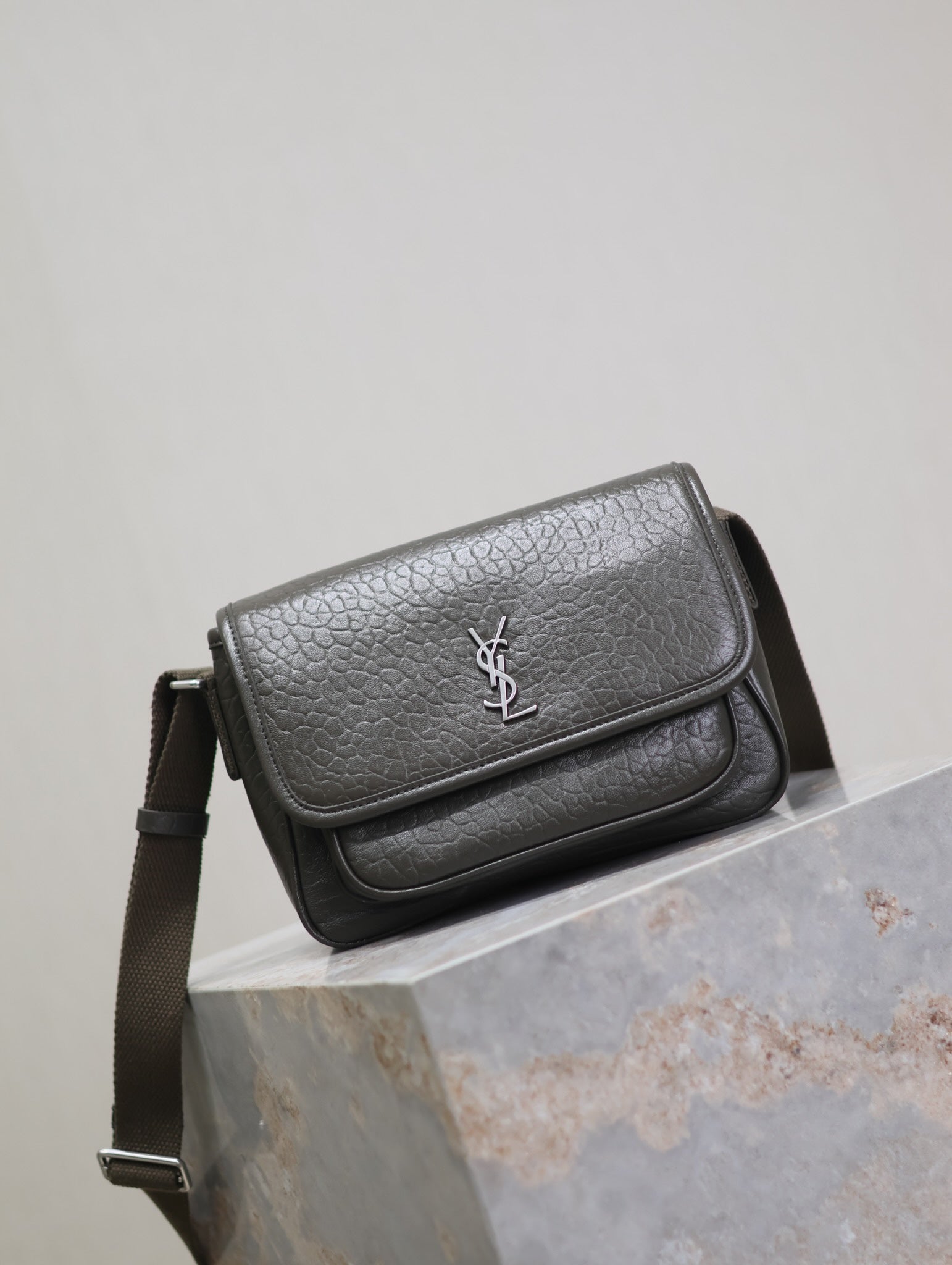 YSL flap crossbody bag angled front view in dark textured leather, silver logo
