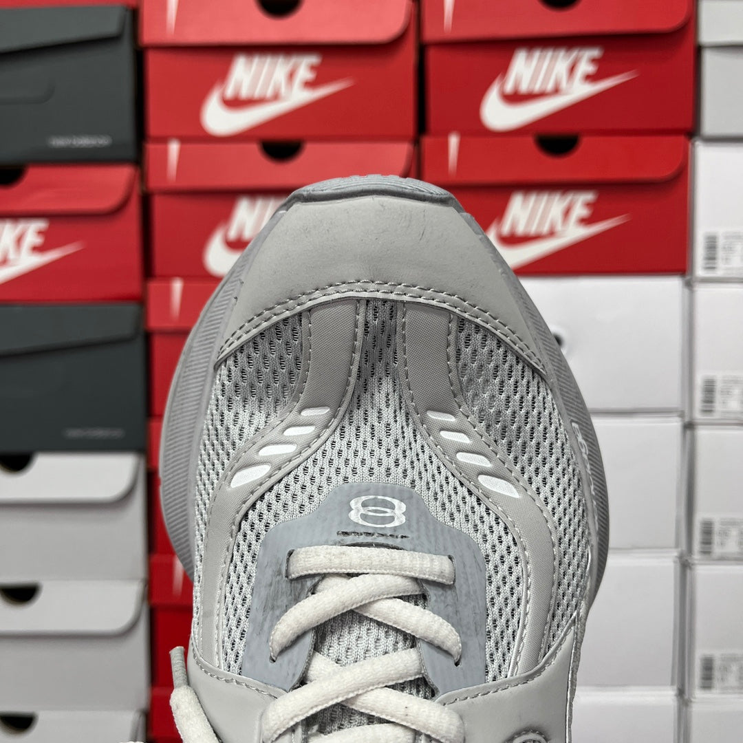 Light gray shoe toe view with mesh paneling and lace-up front