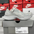 Light gray lace-up running shoes on a box; knit upper and sculpted cushioning sole
