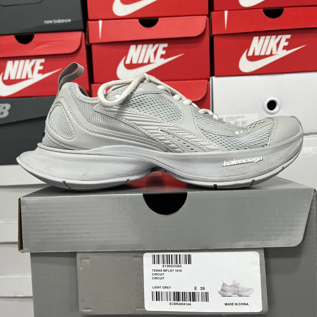 Light gray lace-up running shoes on a box; knit upper and sculpted cushioning sole