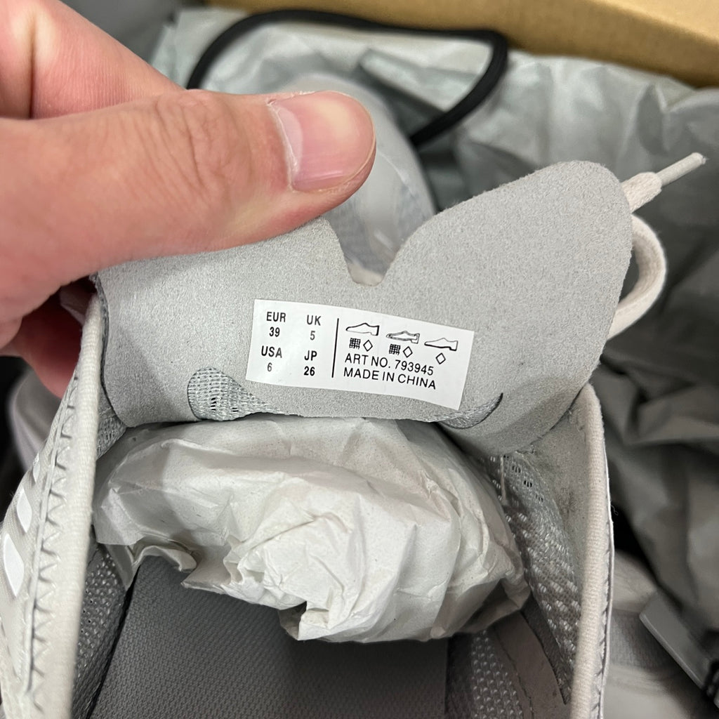 Light gray shoe with size label inside; unisex lace-up running shoe