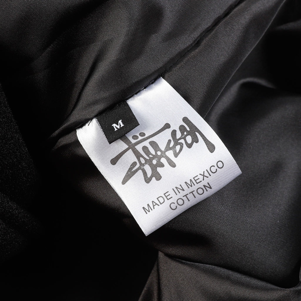Black varsity jacket size label showing M and Made in Mexico, cotton