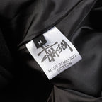 Black varsity jacket size label showing M and Made in Mexico, cotton