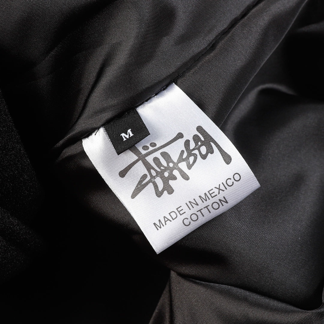 Black varsity jacket size label showing M and Made in Mexico, cotton