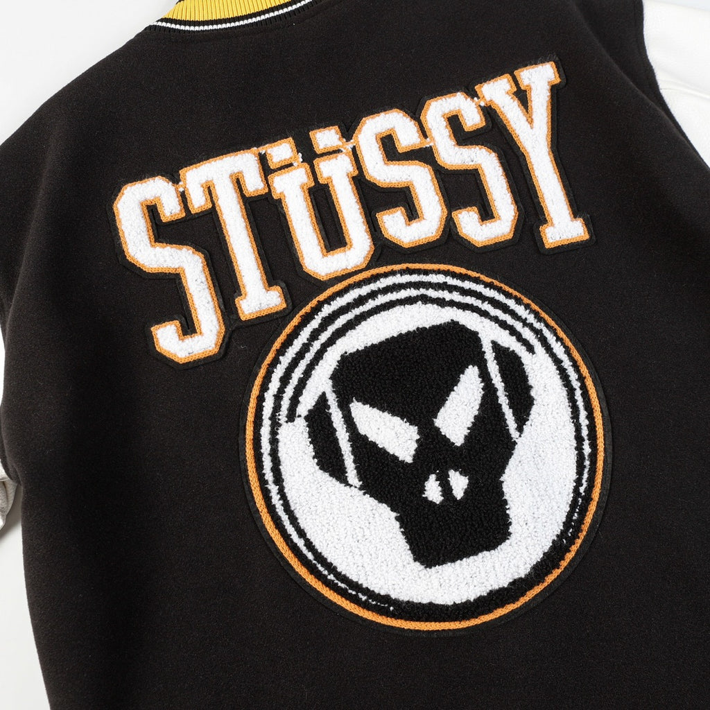 Black varsity jacket front detail with Stüssy lettering and crest patch