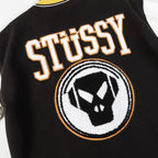 Black varsity jacket front detail with Stüssy lettering and crest patch