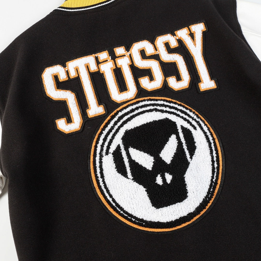 Black varsity jacket front detail with Stüssy lettering and crest patch