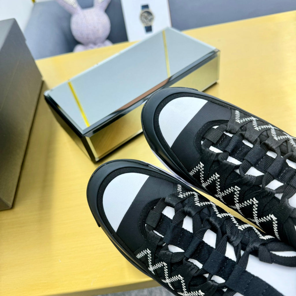 Close-up of black lace-up sneakers showing patterned upper and white side sole trim