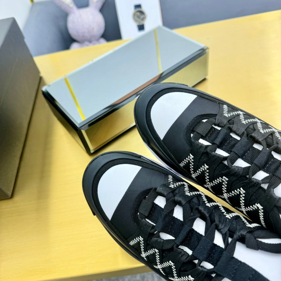 Close-up of black lace-up sneakers showing patterned upper and white side sole trim