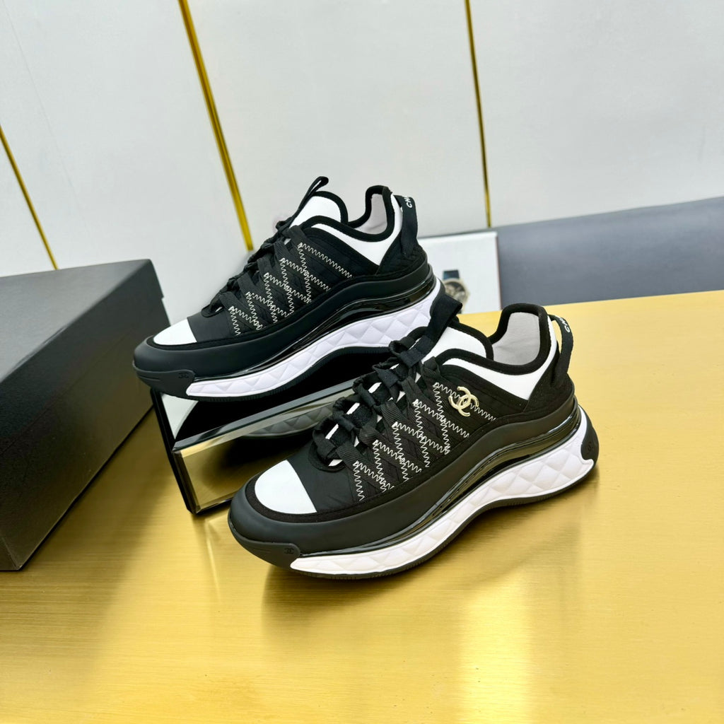 Black lace-up sneakers with patterned textile upper, white side stripe, and thick sole