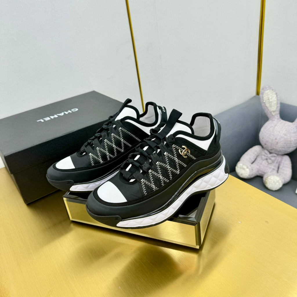 Black lace-up sneakers on display with patterned upper, white accents, and chunky sole