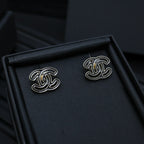 CC logo stud earrings in a black jewelry box, silver-toned with black enamel