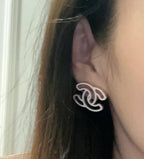 CC logo stud earrings on ear, silver-toned with black enamel and curved shape