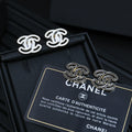 CC logo stud earrings with silver-toned outlines on a black accessory box