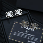 CC logo stud earrings with silver-toned outlines on a black accessory box