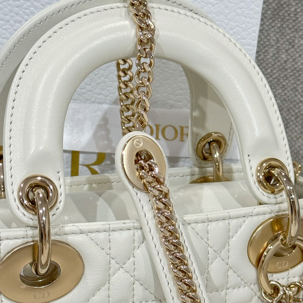 White Dior handbag close-up of interior top with gold-tone rings and chain strap