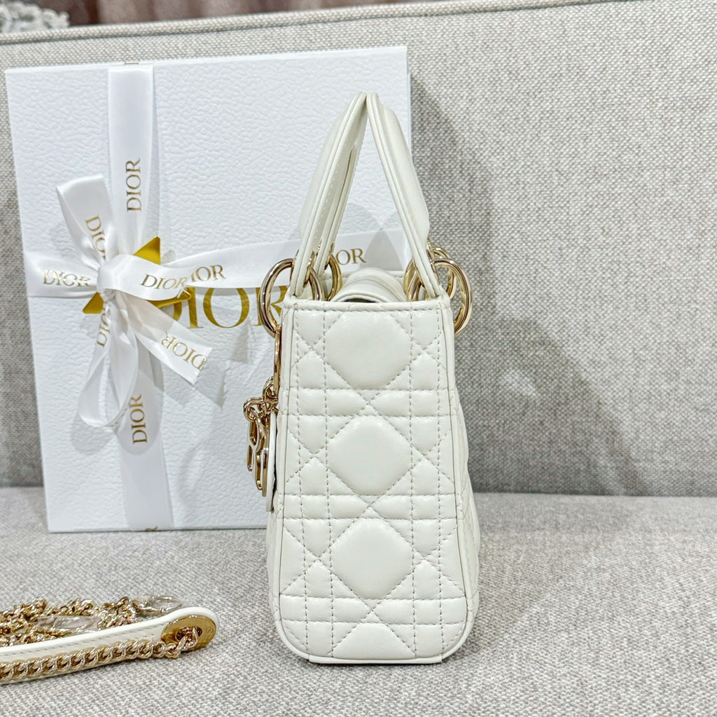 White quilted Dior mini handbag with top handles and gold-tone charm, side angle