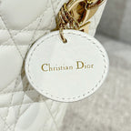 White Dior handbag charm tag reading 'Christian Dior' with gold-tone hardware
