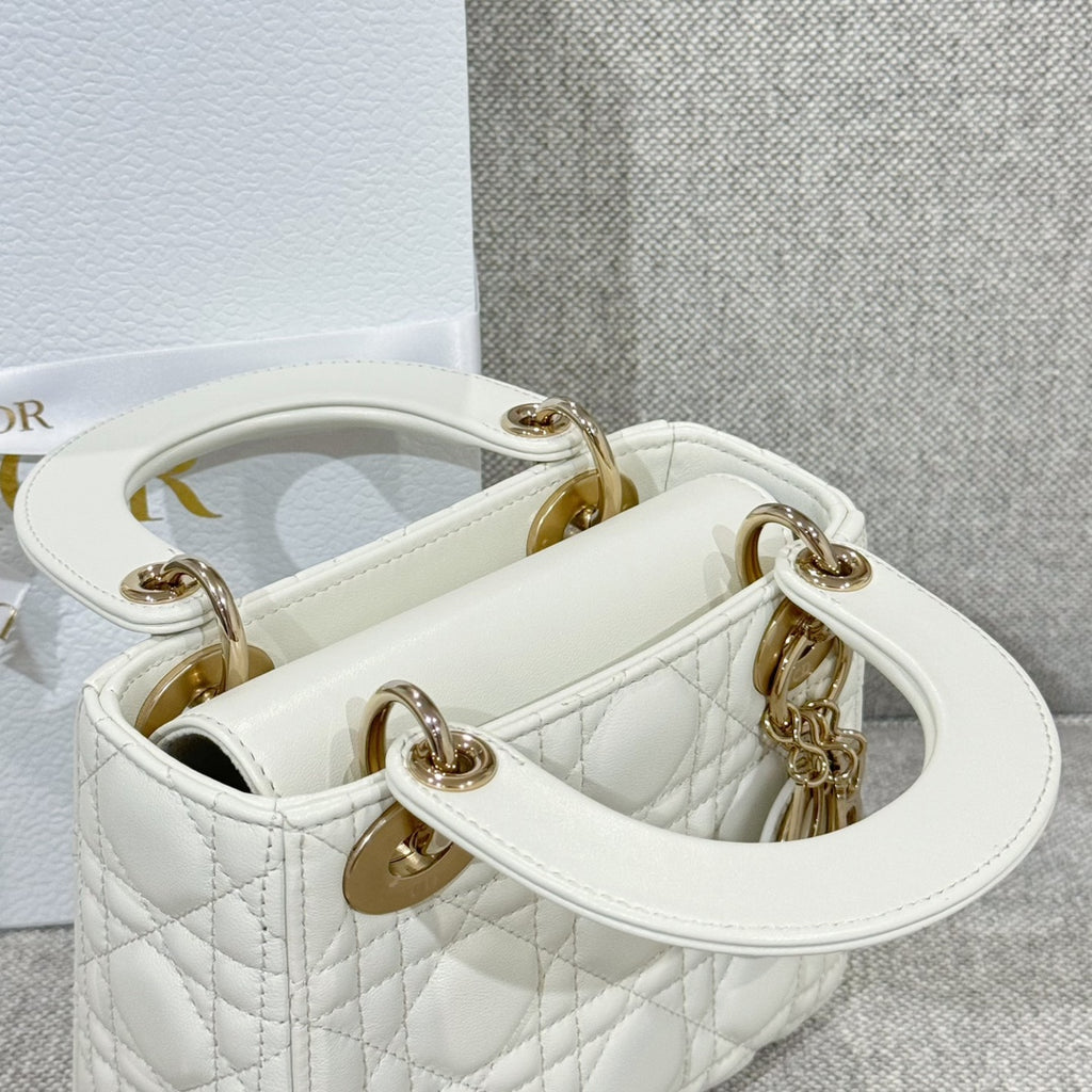 White quilted Dior handbag open top showing interior and gold-tone handle rings