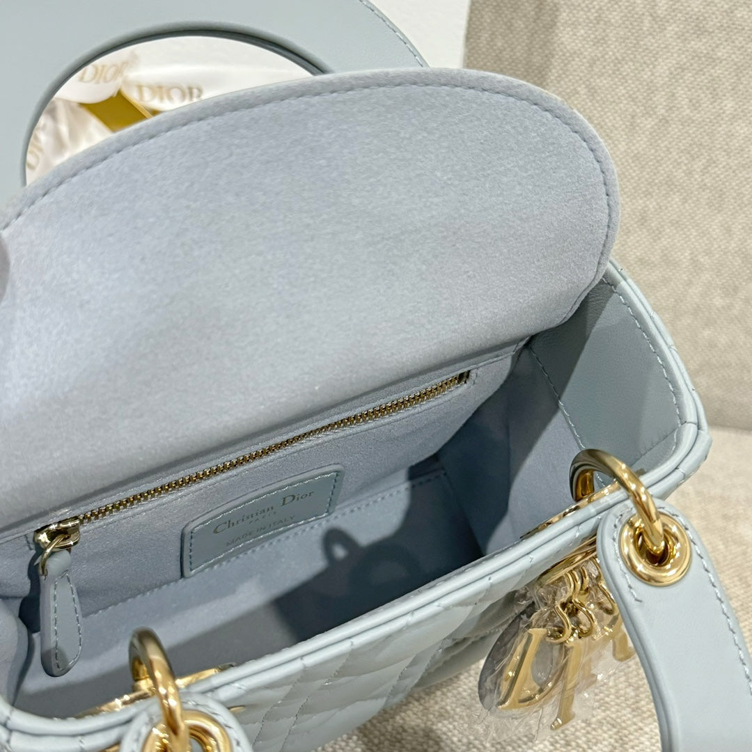 Light blue quilted handbag interior view with zip pocket and gold-tone clasp hardware