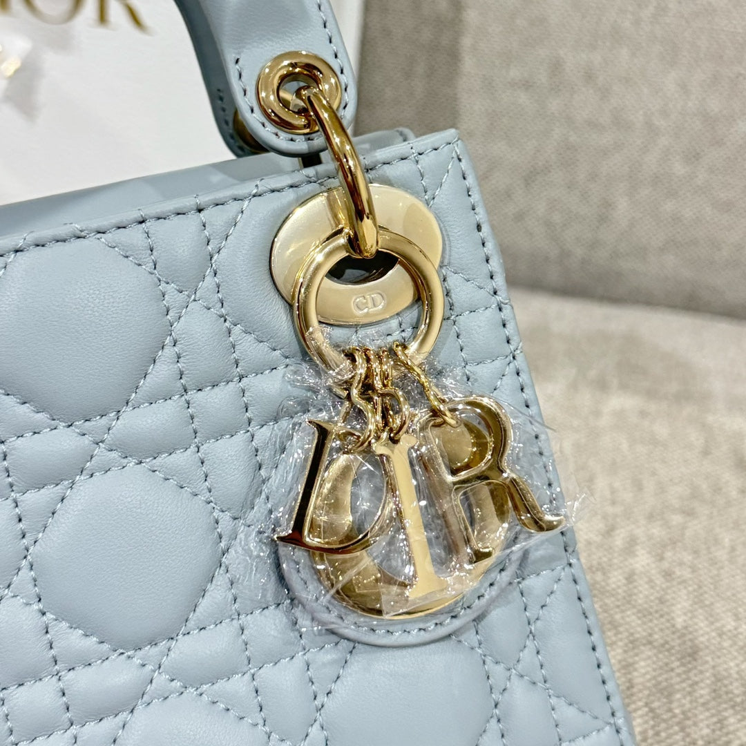 Light blue quilted handbag detail with gold charm drop and ring hardware