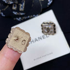 Gold-tone flower stud earrings with Chanel logo center, on display card