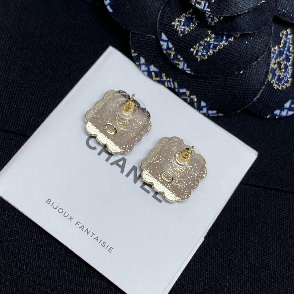 Gold-tone clover stud earrings with Chanel logo center, on display card