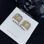 Gold-tone clover stud earrings with Chanel logo center, on display card