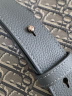 Dior crossbody bag strap end with snap button on gray textured leather trim.