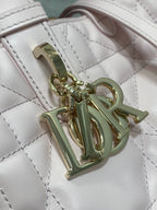 Dior handbag close-up of gold chain charm on quilted light pink leather