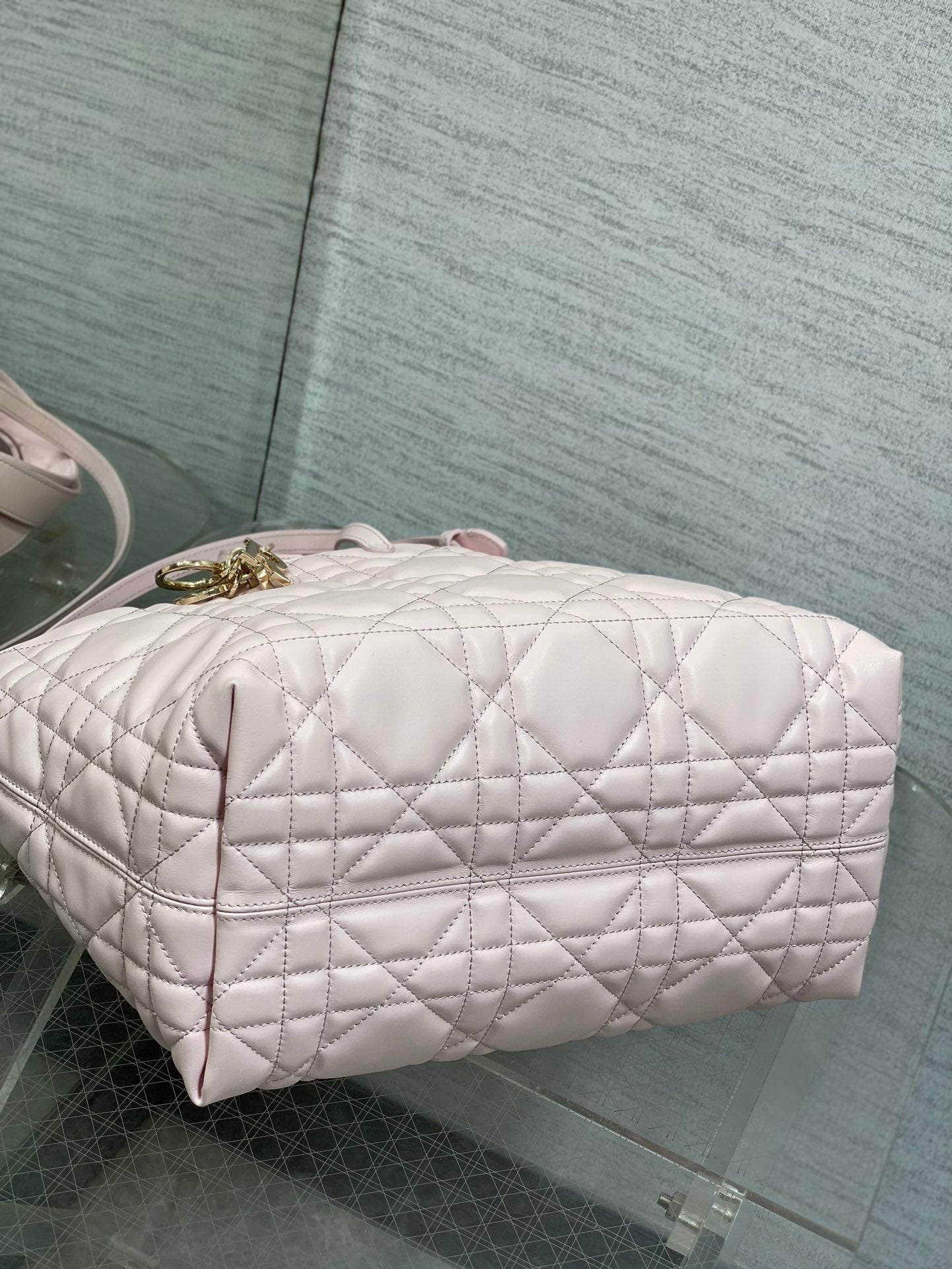 Dior handbag side view with quilted light pink body and gold zipper pull