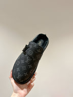 Black Louis Vuitton monogram slide sandal held in hand, side view with buckle strap