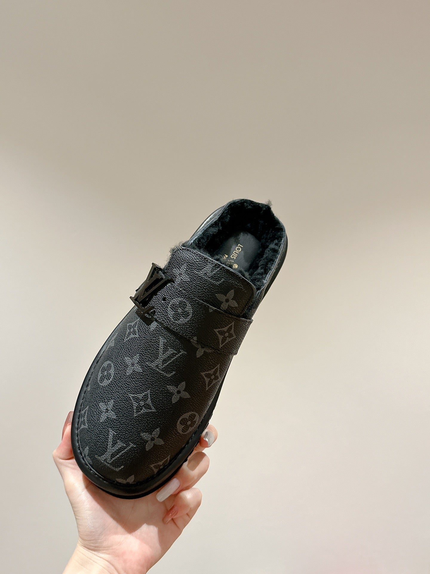 Black Louis Vuitton monogram slide sandal held in hand, side view with buckle strap