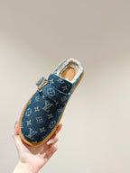 Blue Louis Vuitton monogram slide sandal with fur lining and tan sole, held upright.
