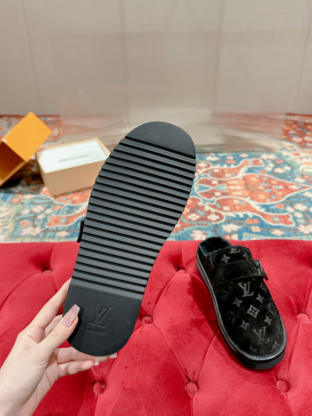 Sandal soles and one Louis Vuitton black monogram slide on red upholstered surface