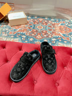 Louis Vuitton black velvet monogram sandals on a red tufted bench