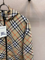 Plaid hooded jacket sleeve with embroidered emblem on beige, navy, and red fabric