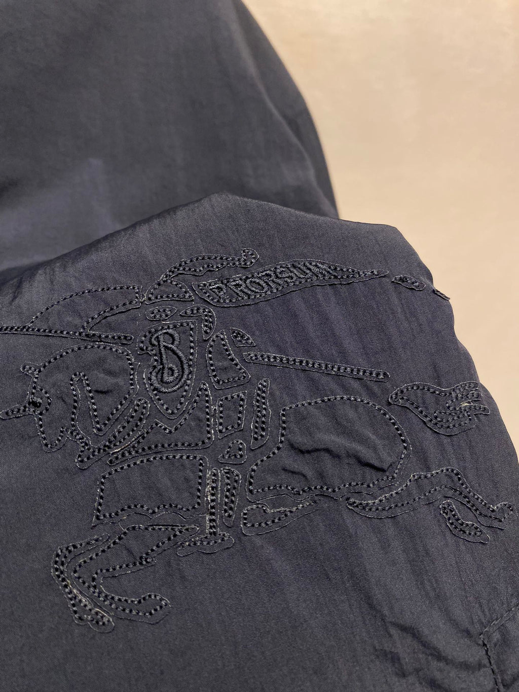 Navy jacket with ornate embroidered cross emblem on sleeve