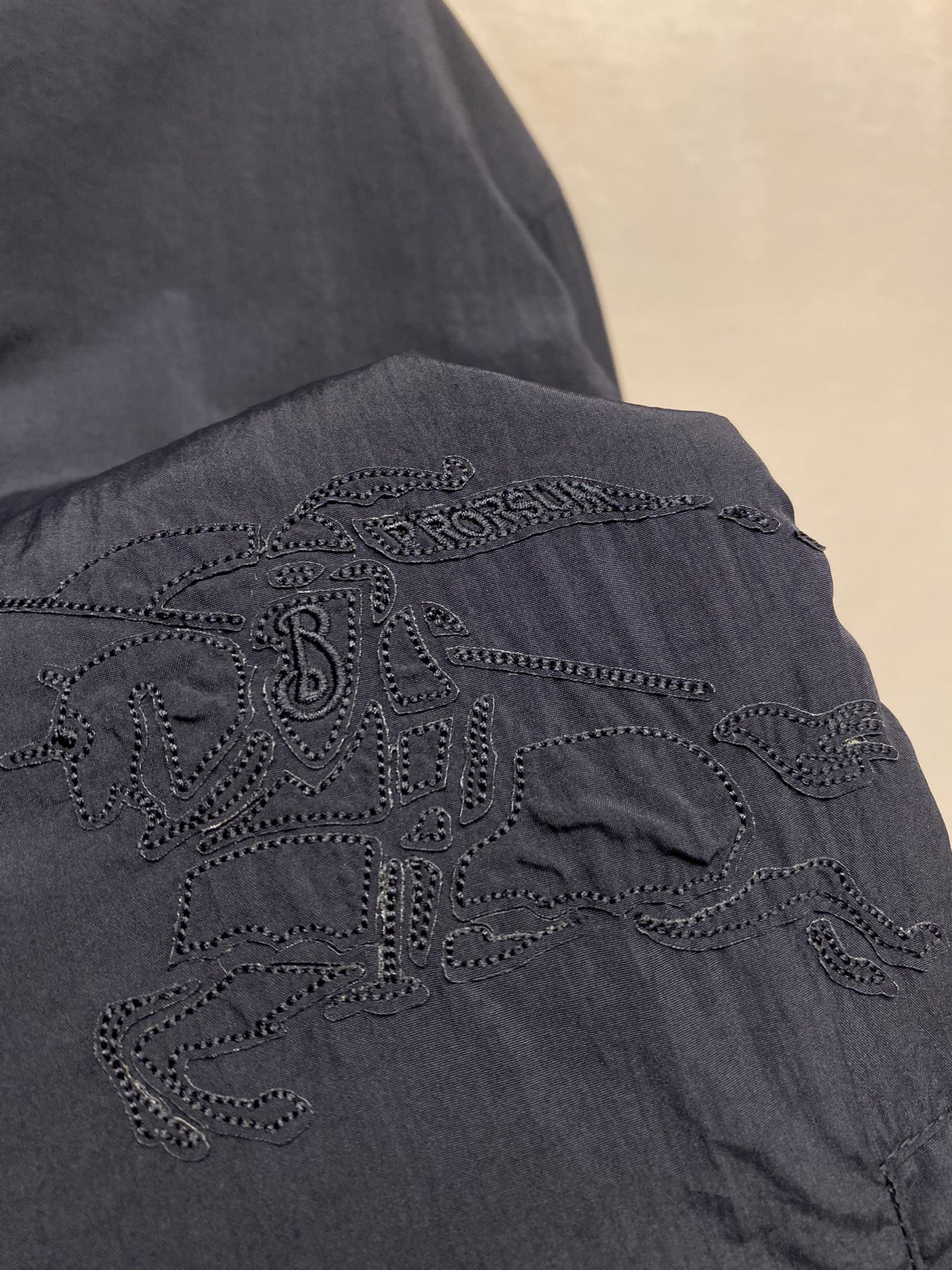 Navy jacket with ornate embroidered cross emblem on sleeve