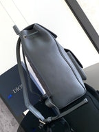 Gray leather backpack bag with rounded top handle, adjustable straps, and front zipper pocket