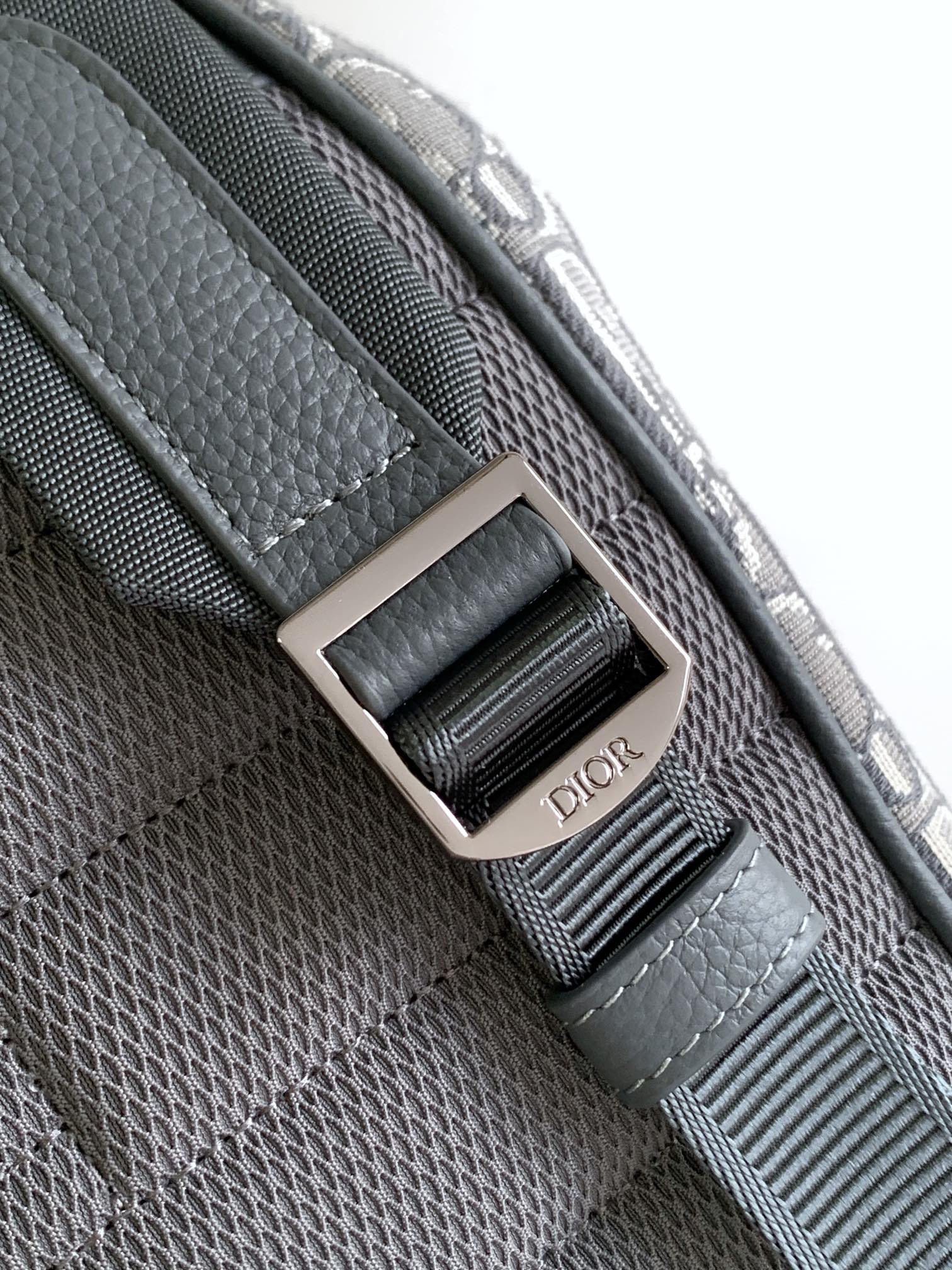 Dior bag close-up of gray woven strap with silver square buckle and Dior lettering
