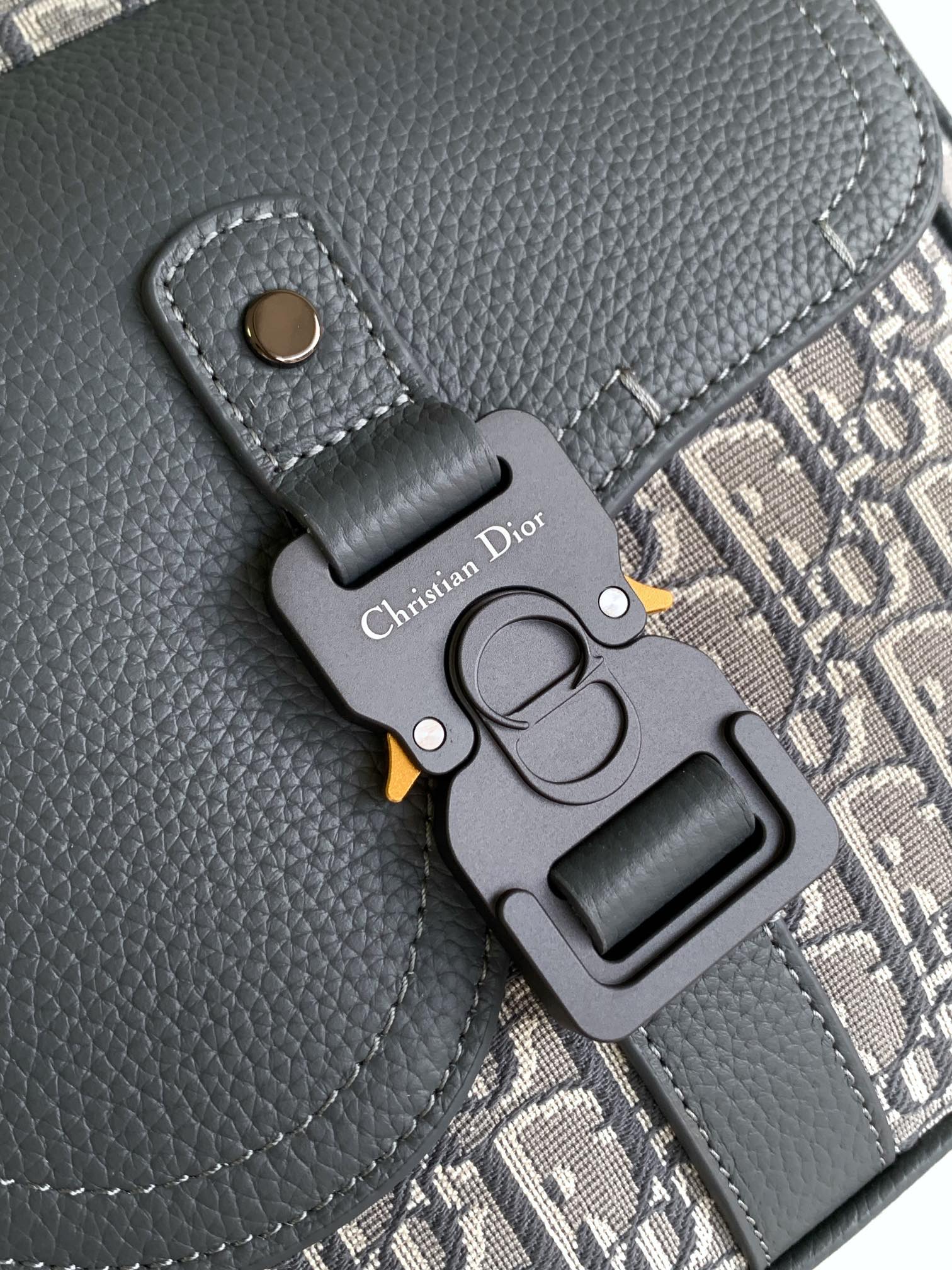Gray Dior bag key fob with metal clasp and embroidered logo on leather