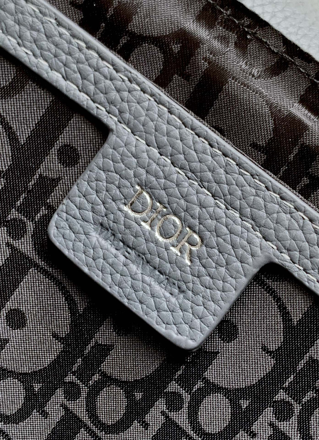 Dior bag logo patch with embossed Dior lettering on gray leather