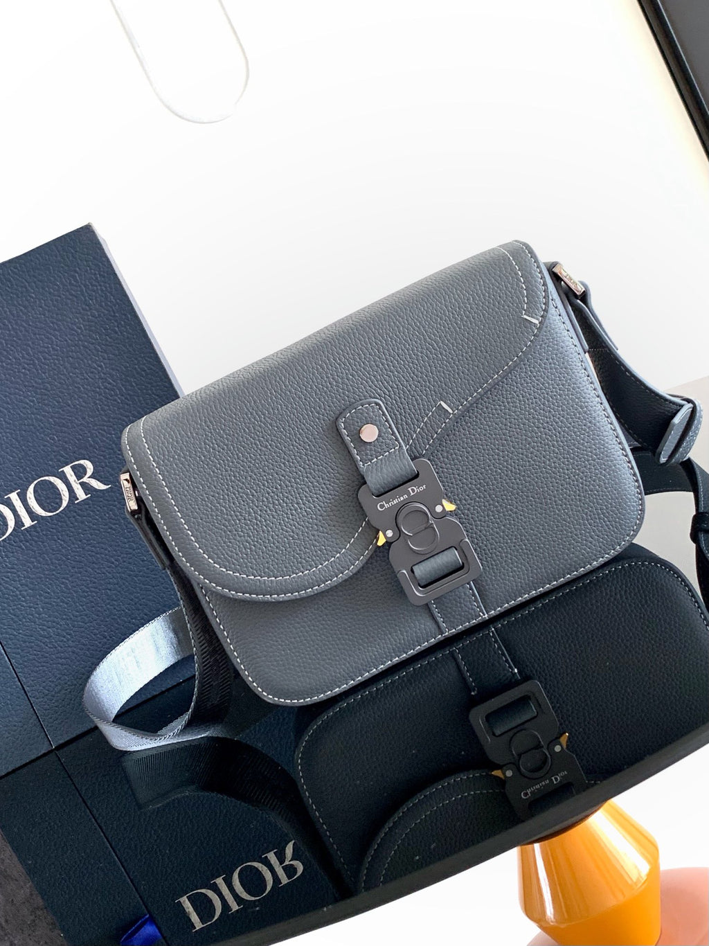 Men's blue-gray leather crossbody bag with flap, buckle strap, and metal hardware
