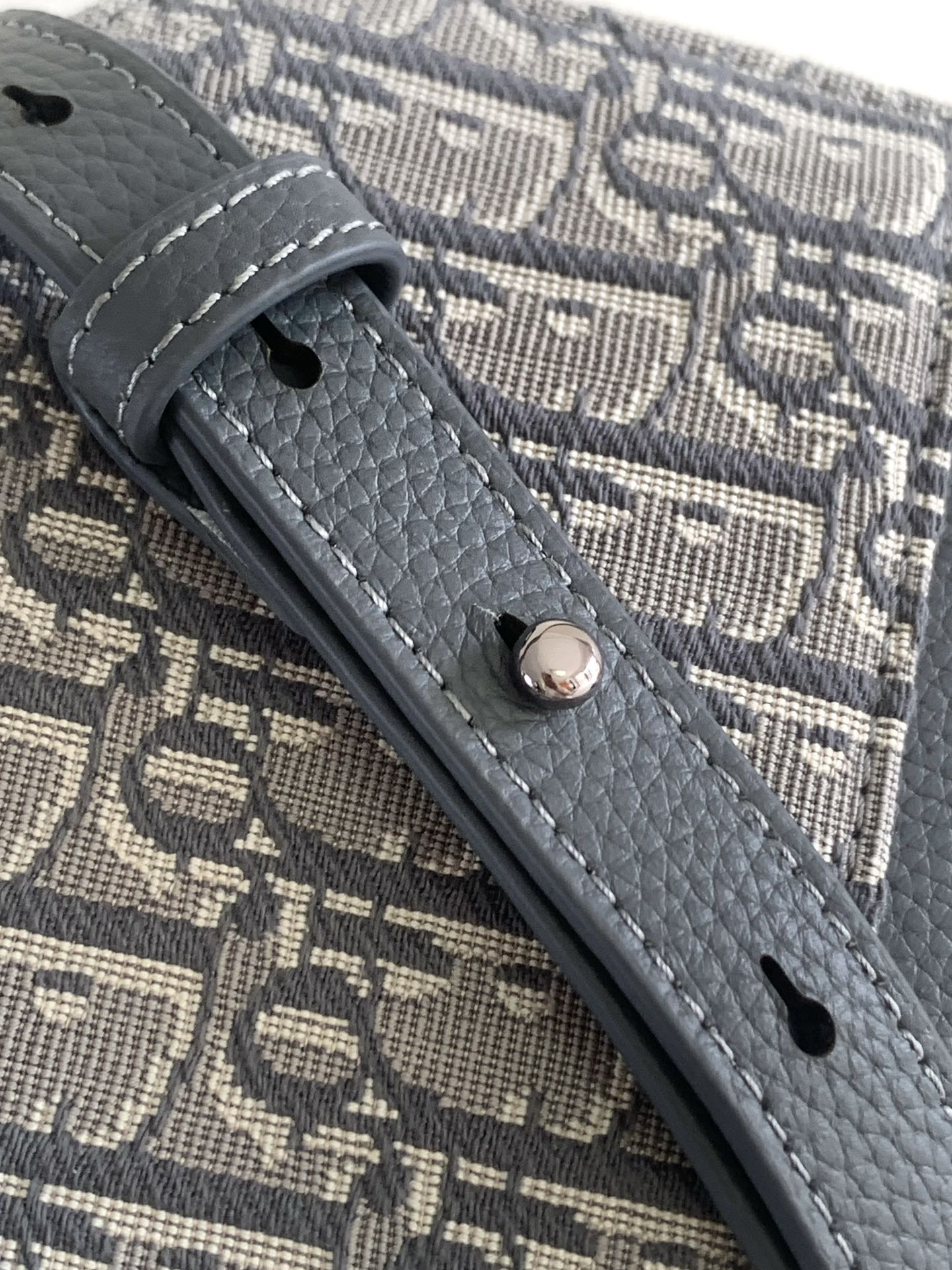 Dior bag close-up of gray leather strap attachment on monogram canvas