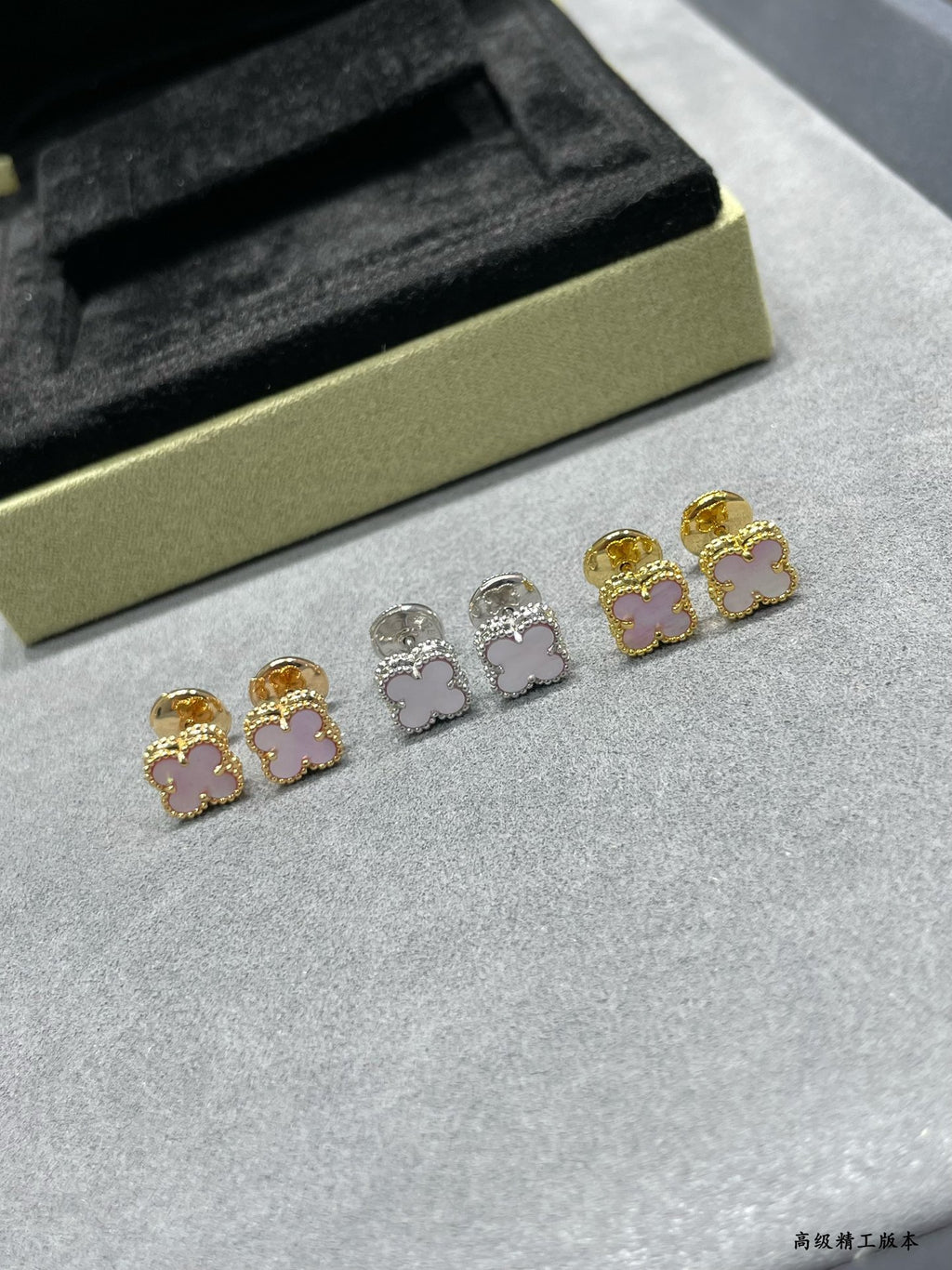 Four-leaf clover stud earrings set: gold and silver with pink enamel, laid out