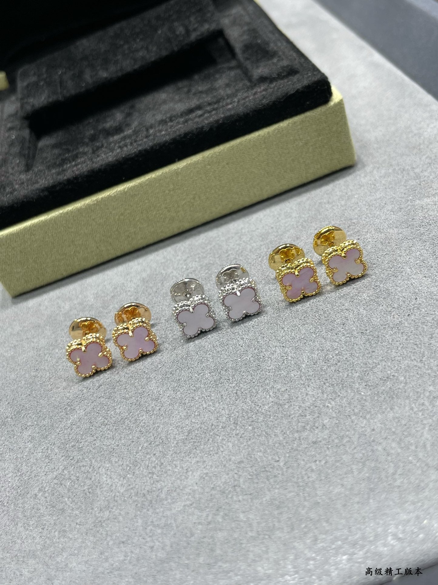 Four-leaf clover stud earrings set: gold and silver with pink enamel, laid out