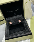 Four-leaf clover stud earrings with pink enamel resting on black velvet