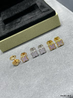 Four-leaf clover stud earrings set on a light surface, mixed gold and silver with pink